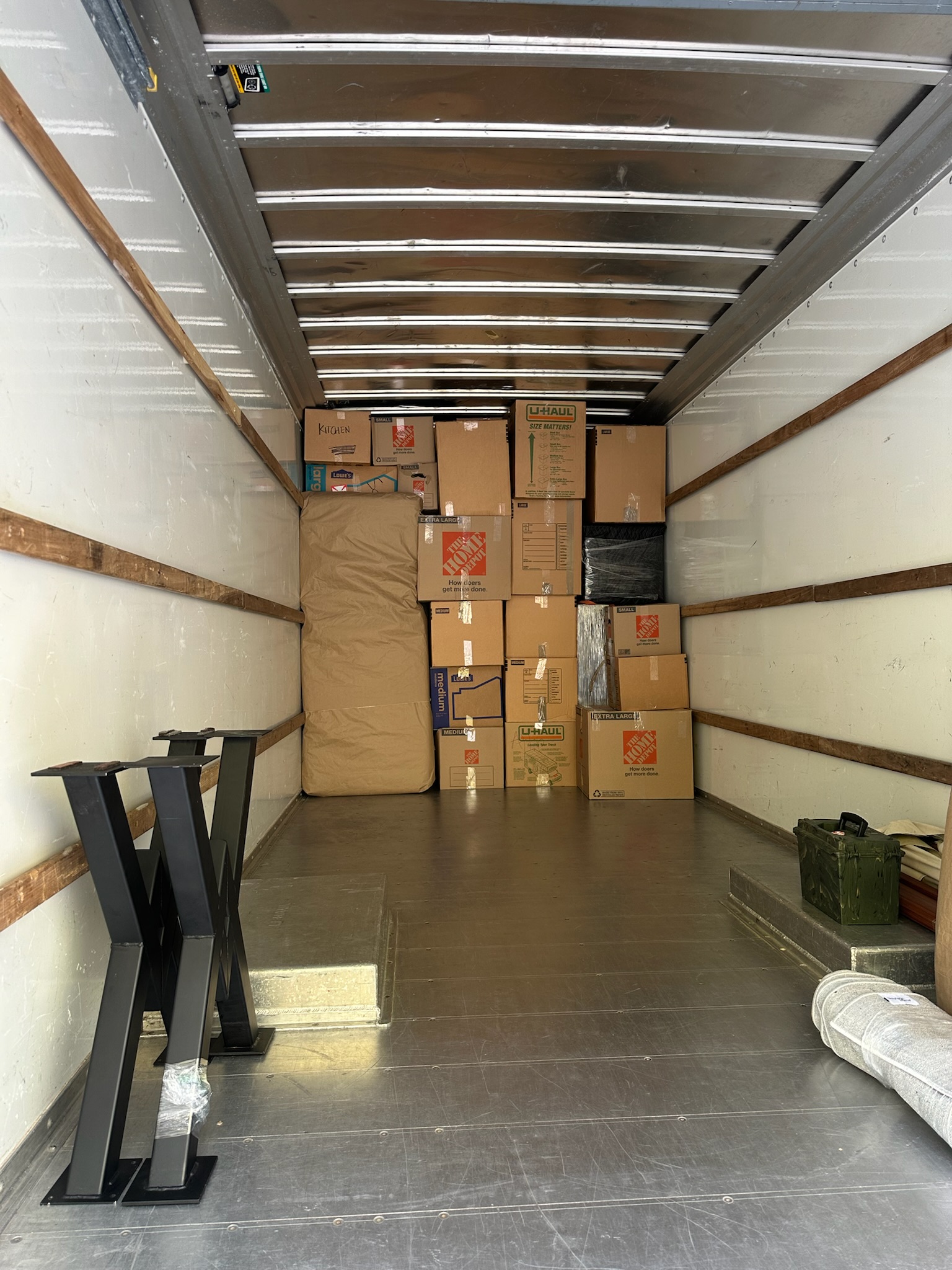 Truck loaded with neatly stacked boxes, a wrapped mattress, and furniture