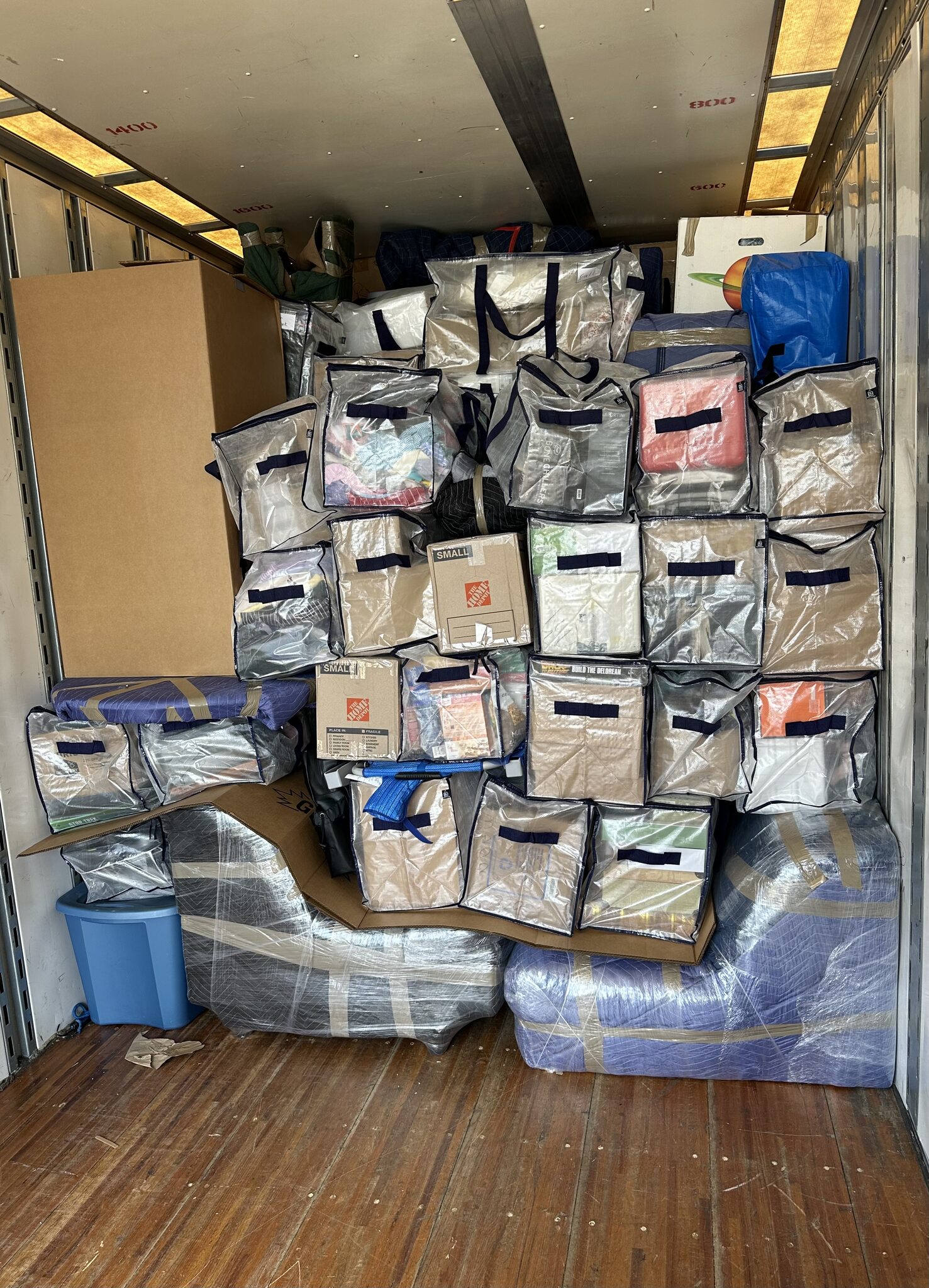 Moving truck packed wall-to-wall with labeled storage bags and totes