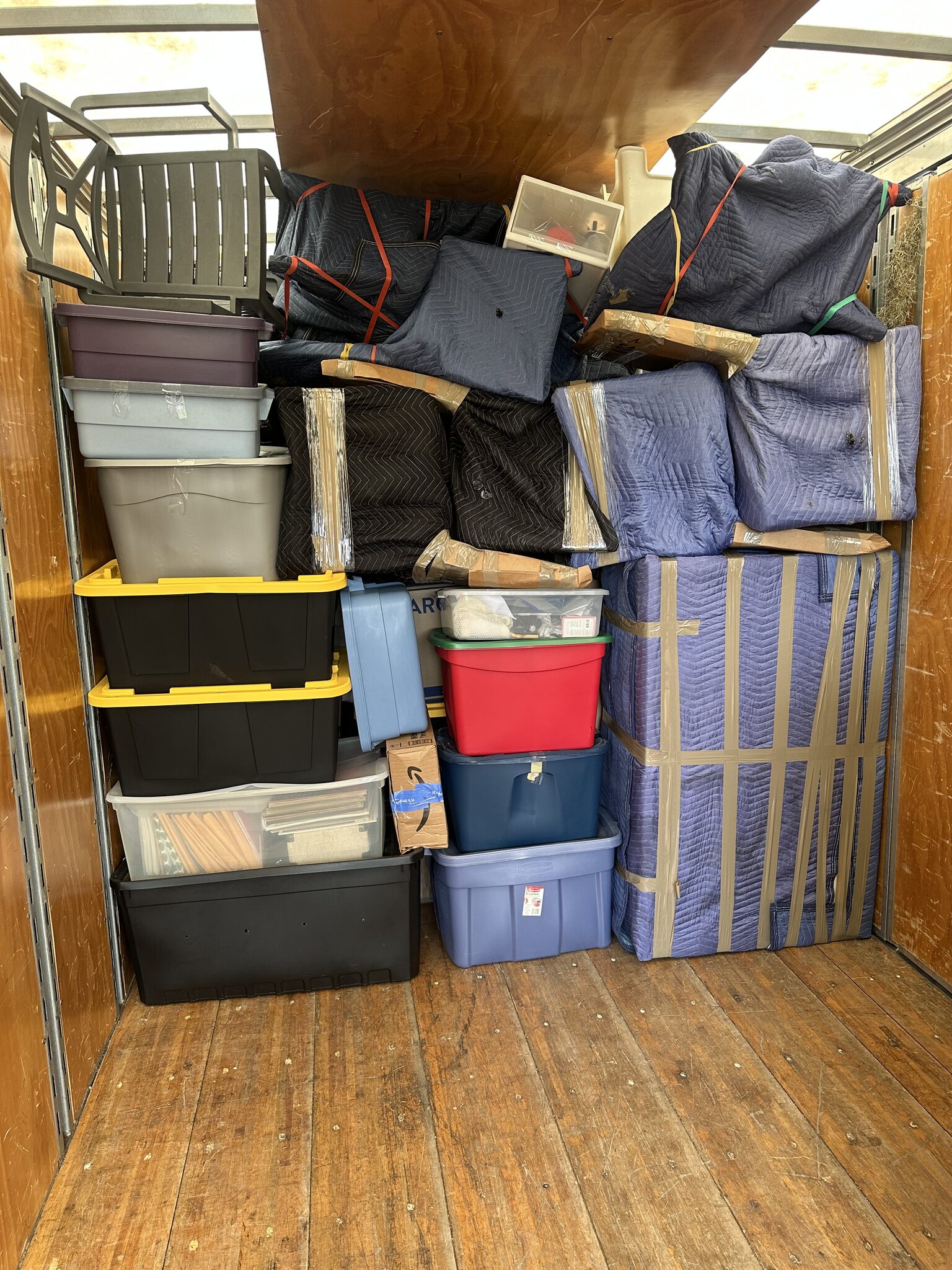 Wrapped furniture and organized storage totes stacked inside the truck