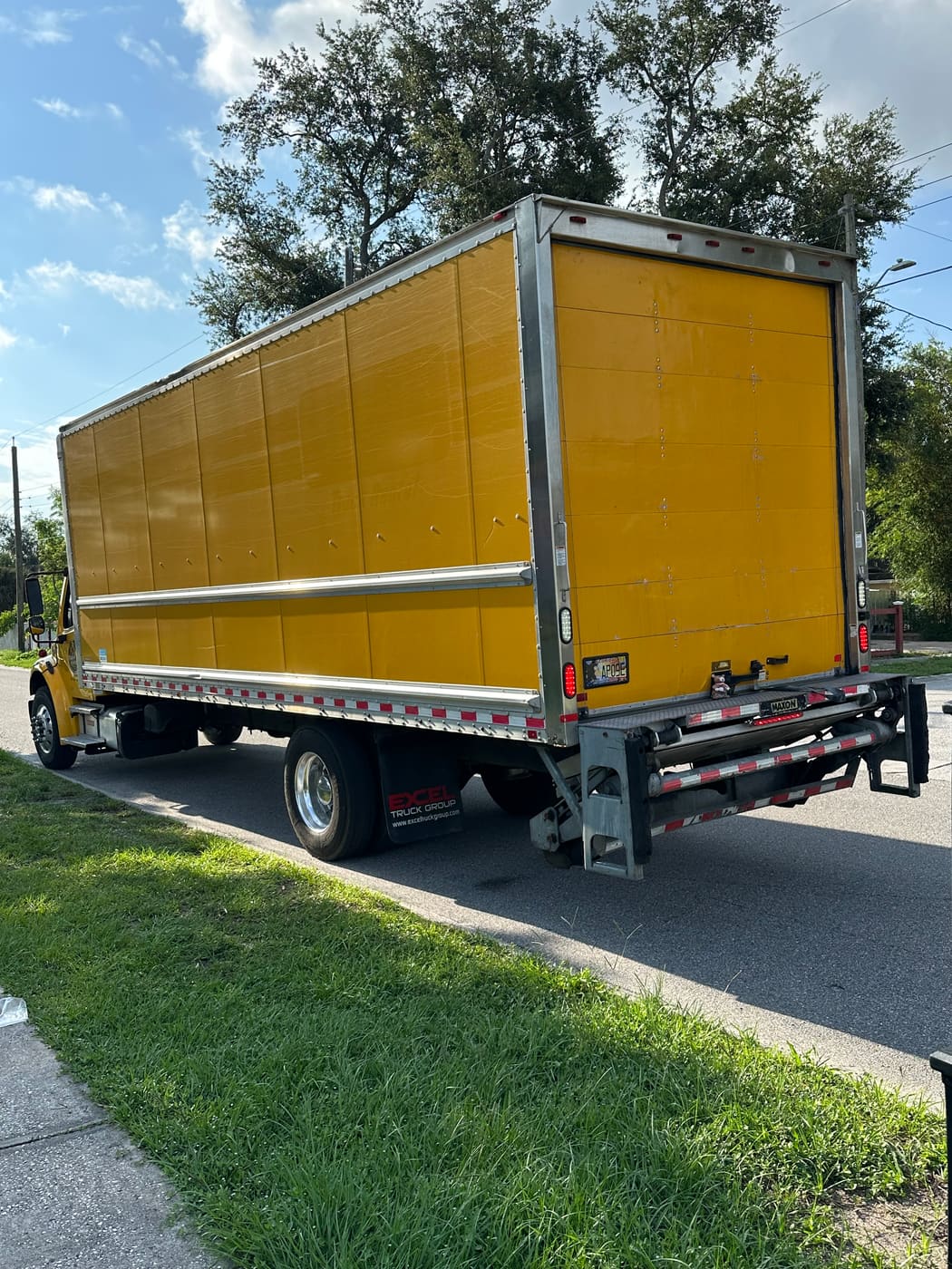 The Above&Beyond box truck parked curbside with its liftgate down and ready to load